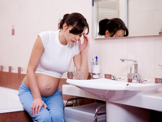 The pregnant woman with a strong toxicosis sitting in bathroom
