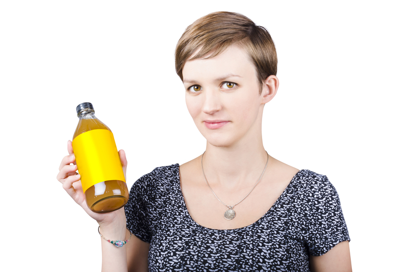 Woman holding glass bottle of apple cider vinegar